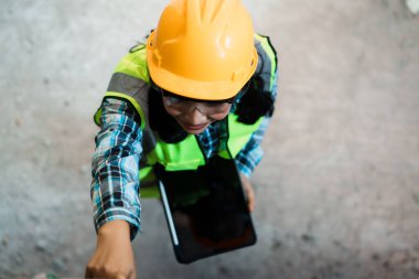 İş sahasında tablet kullanan inşaat işçisi kentsel konum eylemi endüstriyel çevre görüntüleme teknolojisi entegrasyonunu vurdu