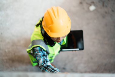 İnşaat işçisi, tablet kentsel çevre ile siteyi inceliyor. Eylem, güvenlik teçhizatı, hava görüşü, sanayi görüşü.