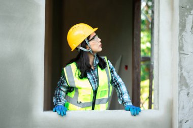 İnşaat işçisi, bina yenileme çalışmaları sırasında inşaat alanında inceleme yapıyor. Parlak çevre, profesyonel tavır.