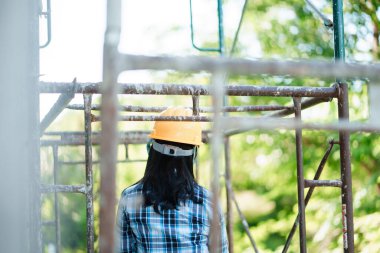 İnşaat işçisi yapı iskelesini gözlemliyor. Dış mekan fotoğrafçılığı. Endüstride doğal ışık arka plan güvenliği.