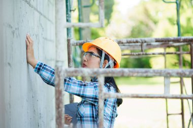 İnşaat işçisi inşaat alanındaki duvar bütünlüğünü değerlendiriyor. Açık hava fotoğrafçılığı. Parlak yakın çekim günü perspektifi.
