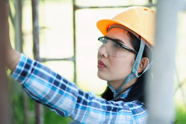 İnşaat güvenliği, koruma ekipmanlı kadın işçiyi dış mekan fotoğrafçılığı doğal ışık yakın çekim perspektifi ile ölçüyor