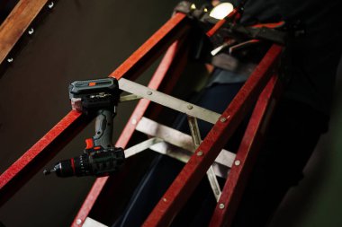 İnşaat işçisi, kapalı alandaki merdivenlerde matkap kullanıyor. Yüksek verimli çalışma alanı odaklı çevre yakın görüntüsü