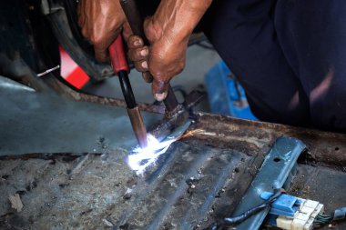 Otomobil tamirhanesinde kaynak makinesiyle kapatılıyor.