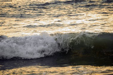 Gün batımında deniz yüzeyinden yansıyan dalgalar ve ışık.