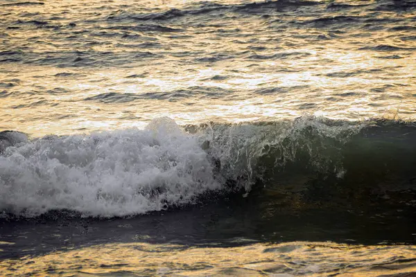 Gün batımında deniz yüzeyinden yansıyan dalgalar ve ışık.