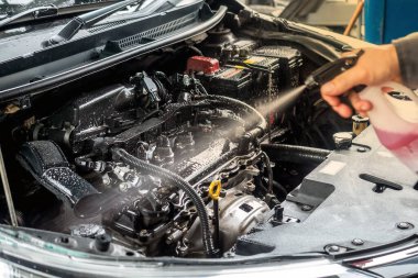 Tamirci, motor bölümünü temizlemek için temizlik spreyi kullanıyor..