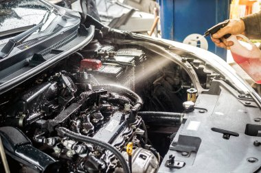 Tamirci, motor bölümünü temizlemek için temizlik spreyi kullanıyor..