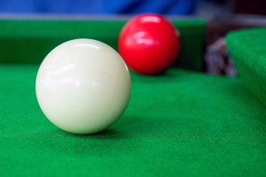Beyaz bilardo topu köşedeki kırmızı topa nişan alıyor.