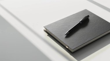 Minimalist beyaz bir yüzeye yerleştirilmiş, sadeliği ve zarafeti vurgulayan parlak siyah bir defter.