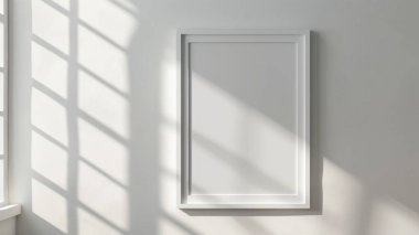 A blank picture frame on a white wall, illuminated by natural sunlight streaming through a nearby window. clipart