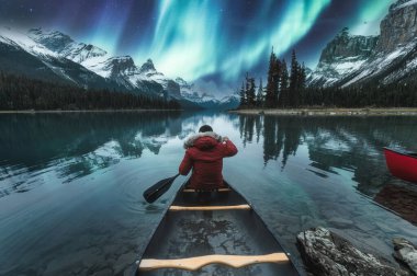 Jasper Ulusal Parkı, AB, Kanada 'da gezgin erkek kanoyla Ruhlar Adası üzerinde güzel bir aurora borealis.