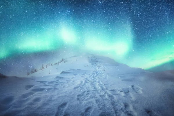 겨울철에 산꼭대기에 발자국 눈덮인 눈덮인 너머로 오로라의 — 스톡 사진