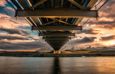 Jokulsarlon buzulu gölü üzerindeki Askılık Köprüsü 'nün alt manzarası. Yazın İzlanda' da gün batımı gökyüzü.