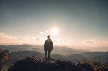 Ulusal parktaki gün batımında dağın tepesinde başarılı bir yürüyüşçü.
