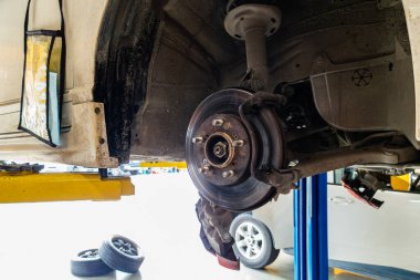 Damaged car and dirty disc brake lifting for maintenance in garage workshop
