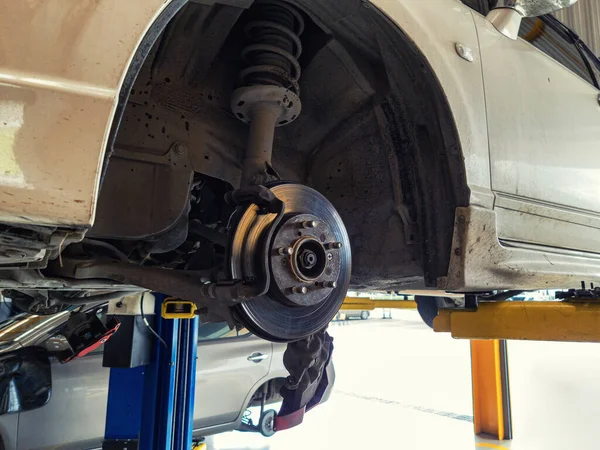 Damaged car and dirty disc brake lifting for maintenance in garage workshop