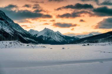 Jasper Ulusal Parkı, Alberta, Kanada 'da kayalık dağlar ve donmuş gölle birlikte Medicine Gölü' nün üzerinde güneşin doğuşunun güzel manzarası.