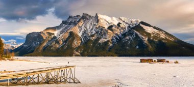 Panorama view of beautiful frozen Lake Minnewanka with rocky mountains in winter on the evening at Banff national park, Alberta, Canada clipart