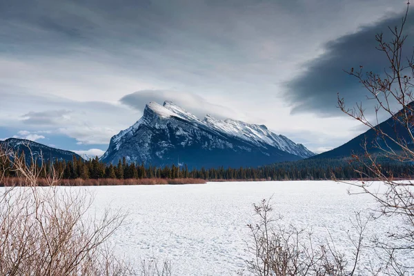 バンフ国立公園 アルバータ州 カナダで晴れた日に冬に覆われた山の謎と雪を持つ冷凍朱色の湖の美しい景色 — ストック写真