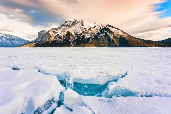 岩だらけの山々と冬のバンフ国立公園 アルバータ州 カナダの冬の湖からの砕けた氷を持つ凍った湖Minnewankaの美しい景色 — ストック写真