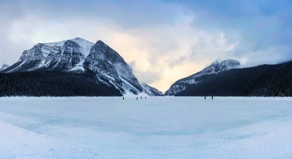 结冰的路易丝湖的风景 多山的岩石 游客们在阴暗的早晨溜冰 — 图库照片