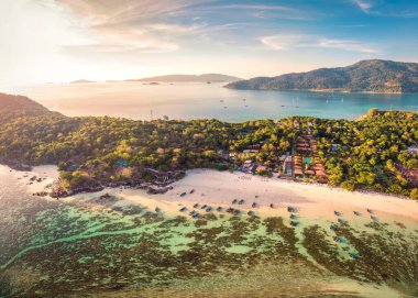 Tropikal deniz, balıkçı teknesi ve yaz tatilinde gün batımında plajda tatil yapan güzel Koh Lipe adasının panorama hava manzarası. Satun, Tayland