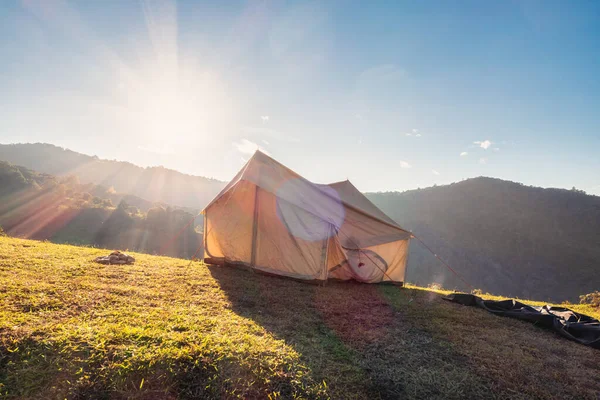 Large tent camping with sunshine on campsite hill in countryside at evening