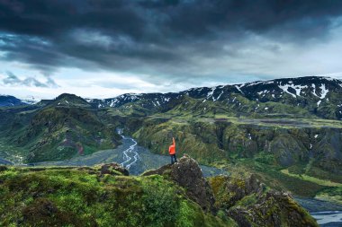 Yazın İzlanda 'nın İzlanda Highlands, Thorsmork, İzlanda' da engebeli volkanik dağların arasında Valahnukur patikasında duran başarılı yürüyüşçünün görkemli karamsar manzarası.