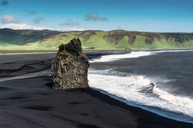 Kirkjufjara 'nın sahnesi, kartal kaya dağı ve yaz aylarında İzlanda' nın güney sahillerine vuran büyük dalgalı kara kumsal sahili.