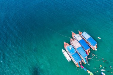 Güneşli bir günde tropikal denizde geleneksel feribot demirli ve turist şnorkelle yüzüyor ve mercan resifleriyle eğleniyor.