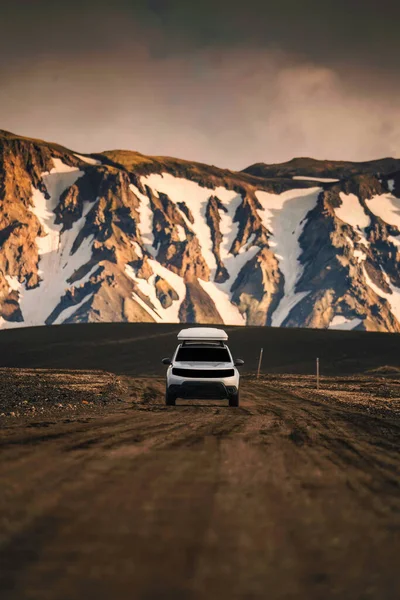 stock image 4x4 SUV car driving on dirt road and volcanic mountain background on Icelandic Highlands in summer at Landmannalaugar, Iceland