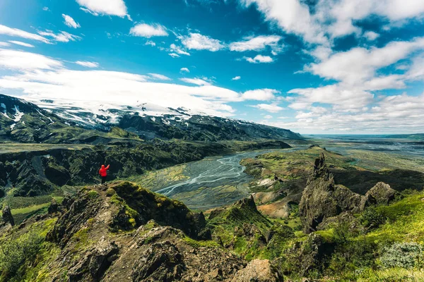 火山の山に囲まれたヴァラフヌクール展望台の上に立つ赤いジャケット姿のハイカーの劇的な姿と アイスランドのソルスモークのアイスランド高地のクロッサ川 — ストック写真