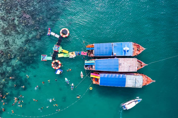 Güneşli bir günde tropikal denizde geleneksel feribot demirli ve turist şnorkelle yüzüyor ve mercan resifleriyle eğleniyor.