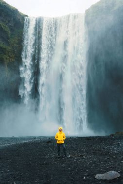 Skogafoss şelalesinin dramatik manzarası yaz mevsiminde İzlanda 'da Asyalı bir kadınla birlikte akıyor.