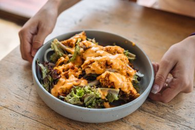 Kızarmış tavuk, marul karışık salata ve mayonez sosuyla ahşap masadaki seramik tabakta.