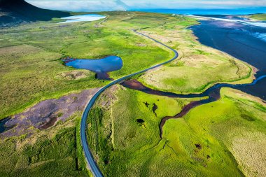 İzlanda 'da yaz aylarında kıyı şeridi boyunca yosunlu ıssız arazide otoban manzarası.
