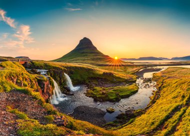 Kirkjufelfoss şelalesi ile birlikte İzlanda 'nın Snaefellsnes yarımadasında, Kirkjufell dağının tepesindeki gündoğumu manzarası