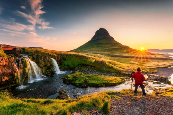 カークフェルフの滝と夏にアイスランドのスナッフェルネス半島に立っている写真家の男性と火山カークフェル山の上に日の出のパノラマ風景 — ストック写真