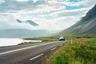 Yol kenarından manzaralı, arabayla vadiden geçen güneşli bir yaz günü İzlanda 'da yollarda sisli bir hava.