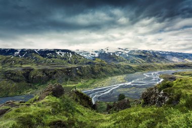 Valahnukur patikasının dramatik volkanik manzarası ve Thorsmork Vadisi 'nde yürüyüş yapan kadın ve İzlanda' nın Highlands 'ında yaz mevsiminde karamsar gökyüzü.