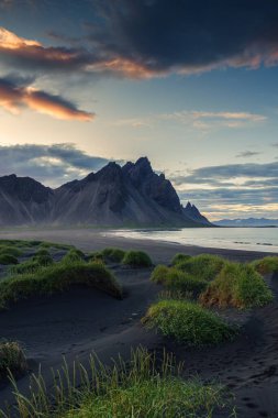 İzlanda 'nın güneydoğusundaki Stoksnes yarımadasındaki siyah kumsalda çimen yığınıyla Vestrahorn dağının güzel manzarası