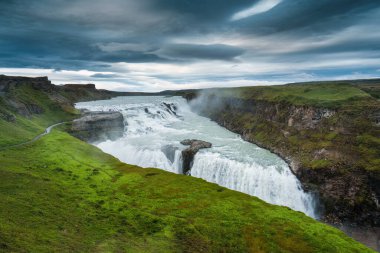 Gullfoss ya da Golden Falls 'un panoramik manzarası Hvita nehrinden akan güçlü şelale ve İzlanda' nın güneybatısındaki kasvetli gökyüzü