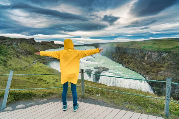 冰岛夏季 穿着黄色夹克的女性游客在峡谷中欣赏格尔弗斯瀑布或金黄色瀑布的景色 — 图库照片
