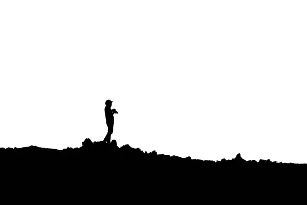 白い背景の山に写真を撮るカメラと一緒に立っている写真家のシルエット — ストック写真