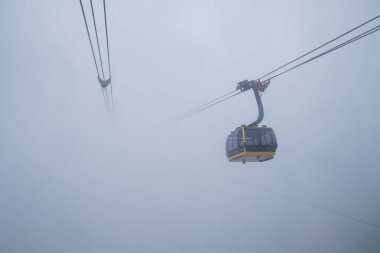 Kablolu araba, Fansipan, Sapa, Vietnam 'da bulutlu bir günde dağda hareket eden yolcuyu taşıyor.