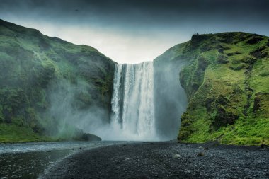 Güçlü Skogafoss şelalesinin güzel manzarası. Skoga nehri yaz mevsiminde İzlanda 'da kasvetli bir günde uçurumdan akıyor.