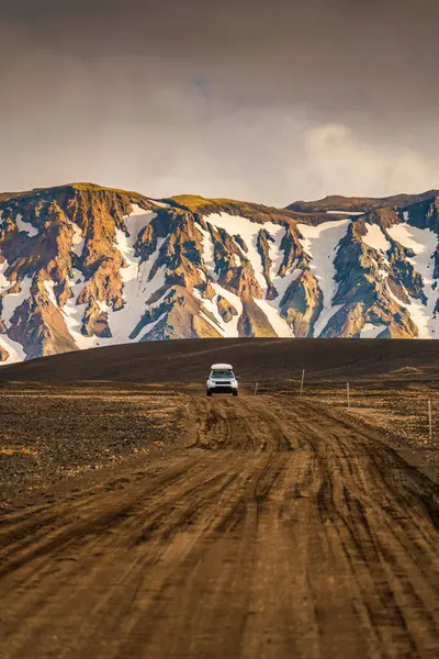 İzlanda 'nın Landmannalaugar şehrinde dört teker çekişli arazi aracı ve volkanik dağ arka planı.