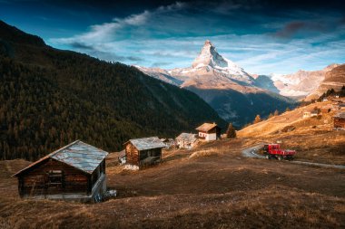 Matterhorn Dağı 'nın güzel manzarası, İsviçre Alpleri, yolda giden kamyon ve sonbaharda İsviçre' nin Zermatt şehrinde tepede ahşap kulübeler.