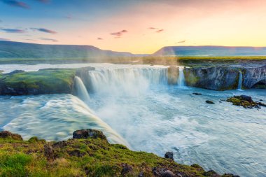 Yazın İzlanda 'nın kuzeyinde Skjalfandafljot nehrinden akan güçlü Godafoss şelalesinin üzerinde gün batımının güzel manzarası.